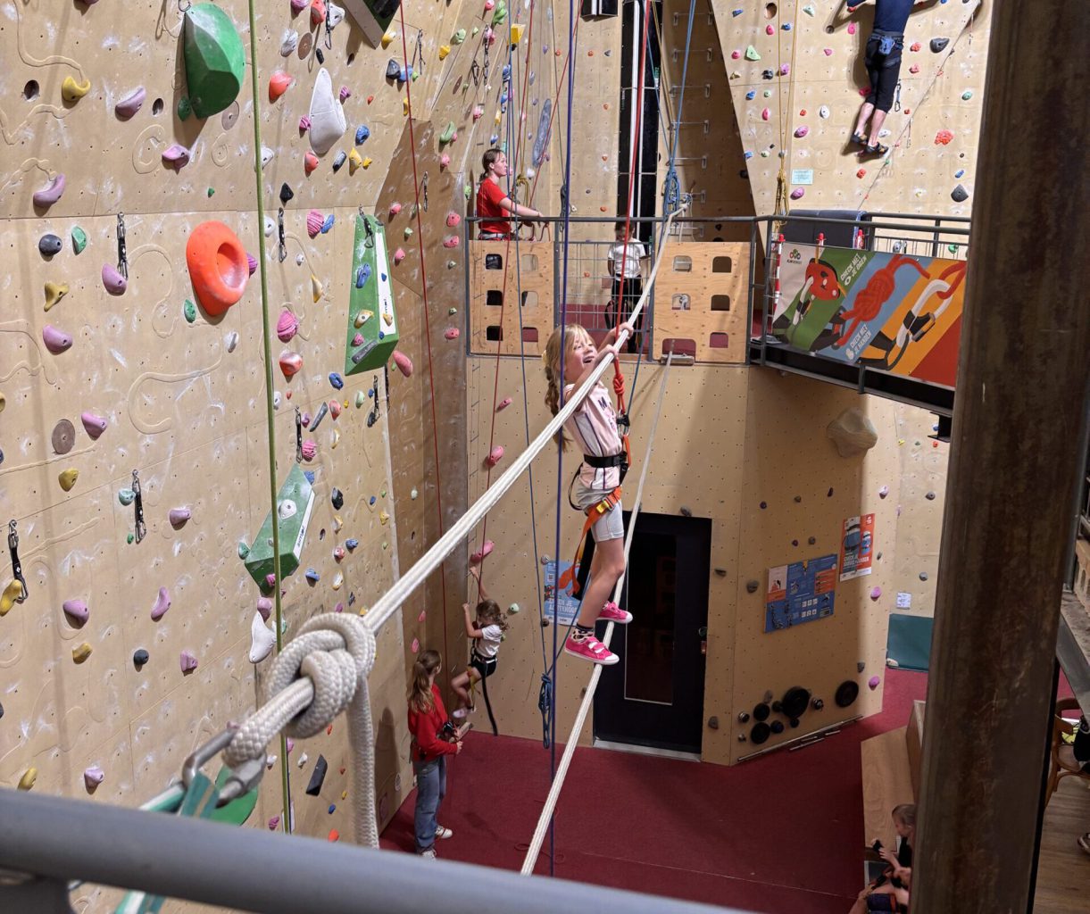 kind beklimt de touwbrug in de klimhal